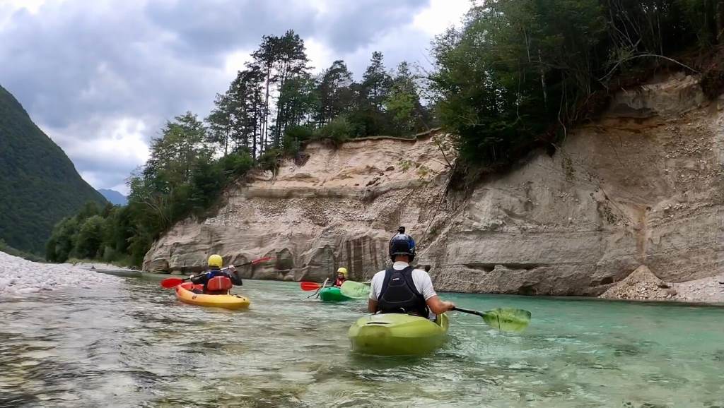 Kayaker paddling emerald waters of Soča River in Soca Valley