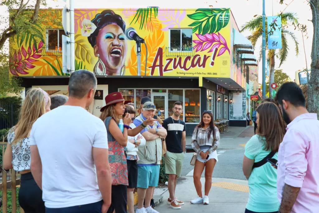 Group enjoying Cuban croquetas on a sunny South Beach food tour amid Art Deco buildings