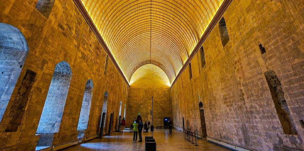 Historic Palais des Papes in Avignon with tourists exploring the grand architecture.